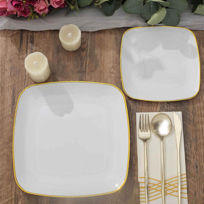 Elegant square plates with gold trim, arranged with cutlery and candles on a wooden table.