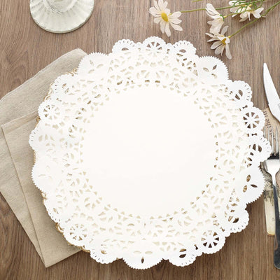 White lace paper doily on wooden table with napkin and flowers.