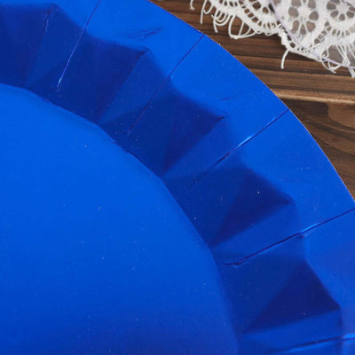 Blue paper plate with scalloped edges on a wooden surface.