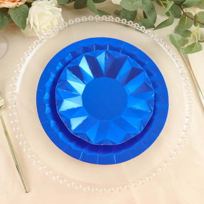 Blue paper plates stacked on a clear charger plate with decorative edges.