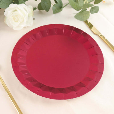Red paper plate on a table with floral and cutlery accents.