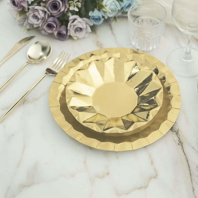 Gold decorative plates on a marble table setting with cutlery and flowers.
