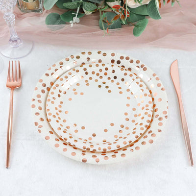 Rose gold polka dot paper plates set on a table with cutlery.