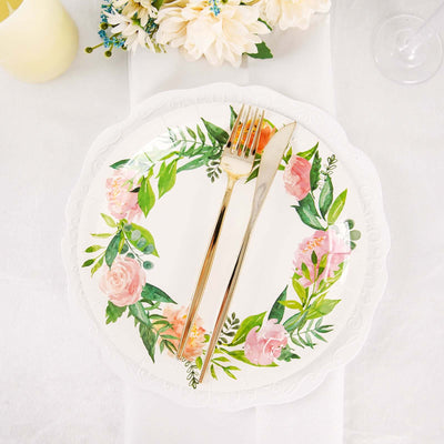 Floral decorative plate with gold cutlery on a table setting.