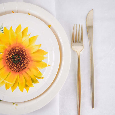 Sunflower-themed paper plate with gold cutlery on a white table setting.