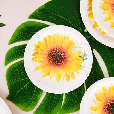 Sunflower-themed paper plates arranged on a green leaf backdrop.