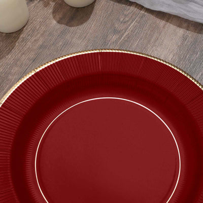 Red paper plate with gold rim on wooden surface.