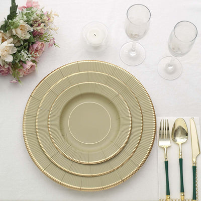 Elegant gold-rimmed dinnerware set on a dining table with floral centerpiece.