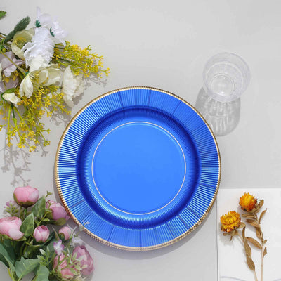 Blue decorative plate on a table with flowers and a glass.