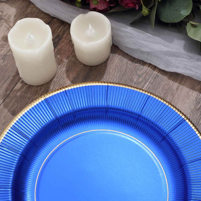 Blue decorative plate with gold rim and white candles on wooden table.