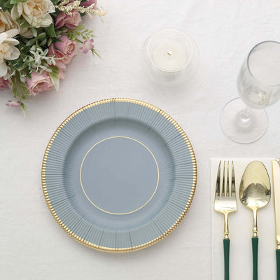 Elegant blue plate with gold rim, set on a dining table with floral arrangement.