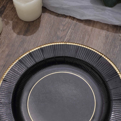 Black decorative plate with gold rim on wooden surface.