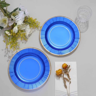 Blue paper plates with gold edges, styled with flowers and a glass.