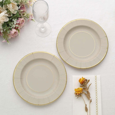 Elegant beige plates with gold rim on a white table setting.