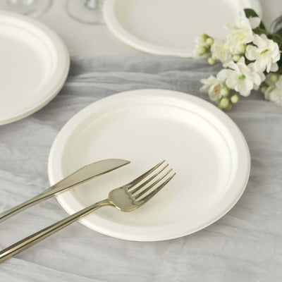 Elegant white disposable plate with gold cutlery on a textured table setting.