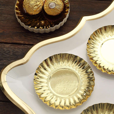 Gold decorative plates on a wooden surface, with chocolate treats in the background.
