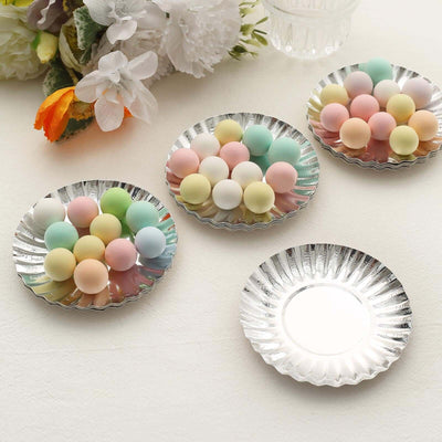 Colorful pastel candy balls arranged on decorative silver plates.