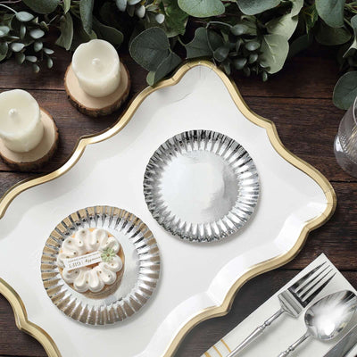 Elegant serving tray with silver plates, cake, candles, and greenery.