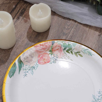 Floral decorative plate with gold rim and candles on wooden table.