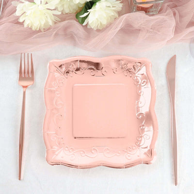 Rose gold decorative plate with elegant design and matching cutlery on a table setting.