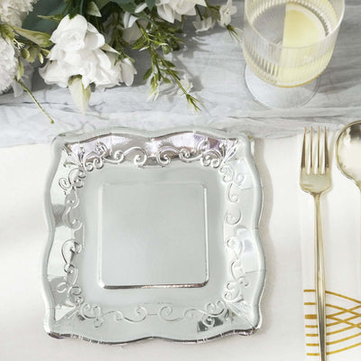 Decorative silver plate on a table setting with floral accents and glassware.