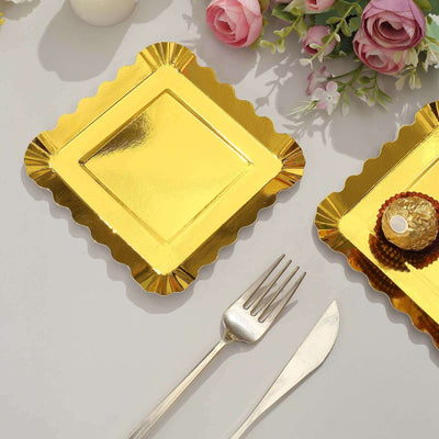 Gold scalloped dessert plates with fork and knife on a table with flowers.