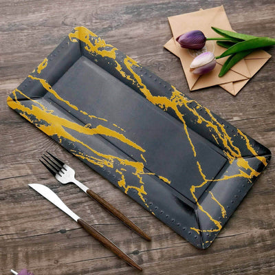 Elegant black serving tray with gold marble design on wooden table.