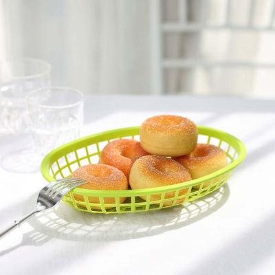 Colorful donuts in a green basket on a white table.