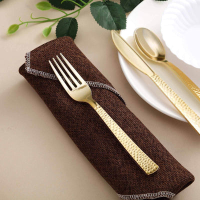 Gold fork on a brown napkin with elegant table setting.