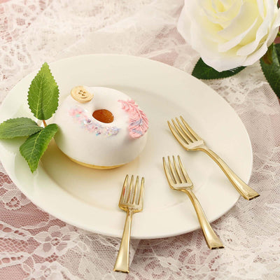 Decorative cake on a plate with gold forks and a rose backdrop.