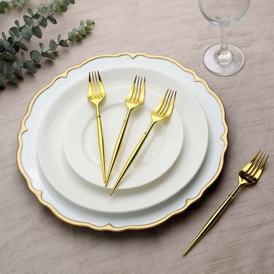 Elegant gold forks arranged on white plates with decorative edges.