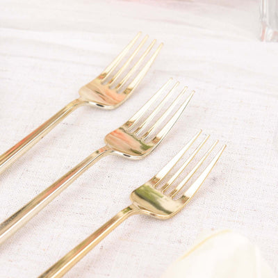 Set of three elegant gold forks on a textured surface.