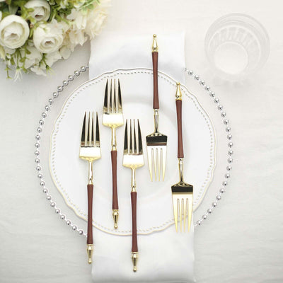 Elegant gold and wood handled forks arranged on a decorative plate.