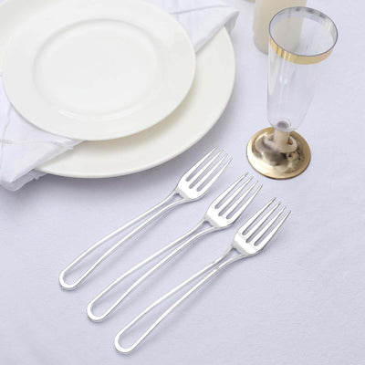 Set of three elegant stainless steel forks on a white tablecloth.