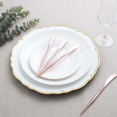 Elegant pink knives on white plates with gold edges, styled on a textured tablecloth.
