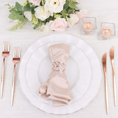 Elegant table setting with rose gold cutlery and a satin napkin.