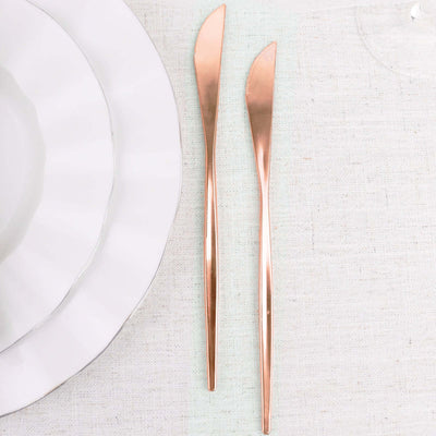 Rose gold butter knives on a textured tablecloth.