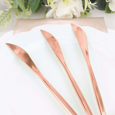 Rose gold butter knives on a white plate with floral decor in the background.