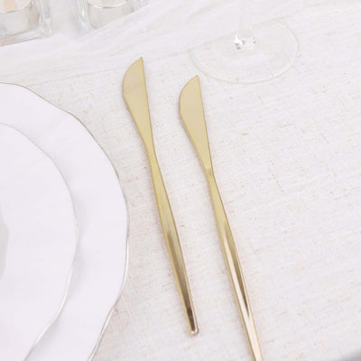 Gold butter knives on a linen tablecloth with elegant plates.