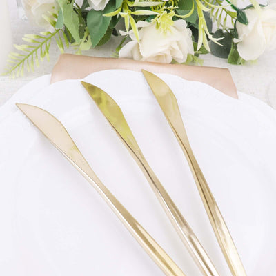 Set of three elegant gold butter knives on a white plate.