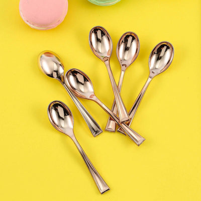 Set of six elegant gold dessert spoons on a vibrant yellow background.