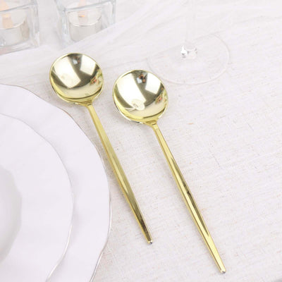 Gold serving spoons on a textured tablecloth with plates and glassware.