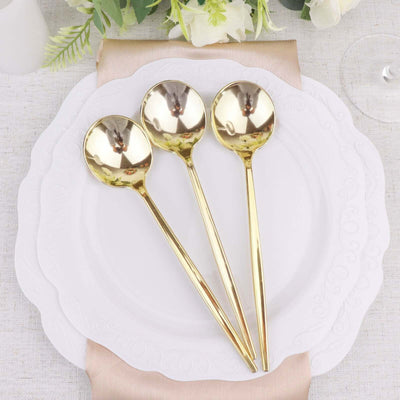 Set of three elegant gold serving spoons on a decorative plate.