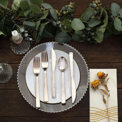 Elegant silverware set on a decorative plate with greenery and floral accents.