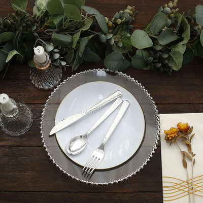 Elegant silver cutlery set on a decorative plate with greenery and candles