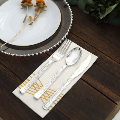 Elegant silver cutlery set on a stylish cloth with decorative details.