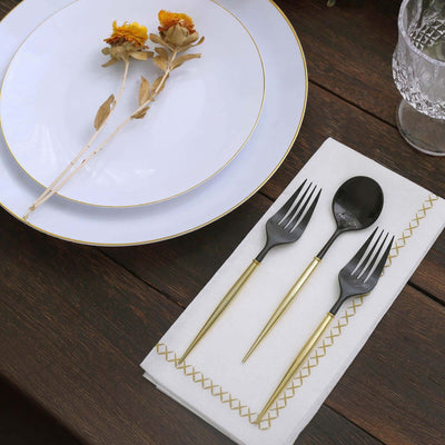 Elegant black cutlery set with gold handles on a white napkin and plate.