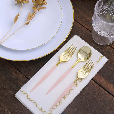 Elegant gold and pink cutlery set on a napkin with a plate and dried flowers.