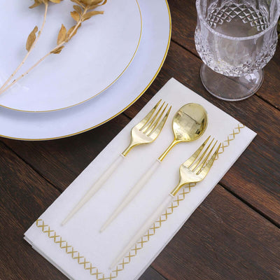 Elegant gold utensils on a white napkin with decorative stitching.