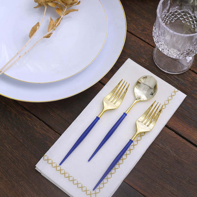 Elegant gold and blue cutlery set on a napkin with a plate and dried flowers.